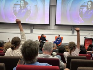 Young girls raising their hands to ask a question of an astronaut