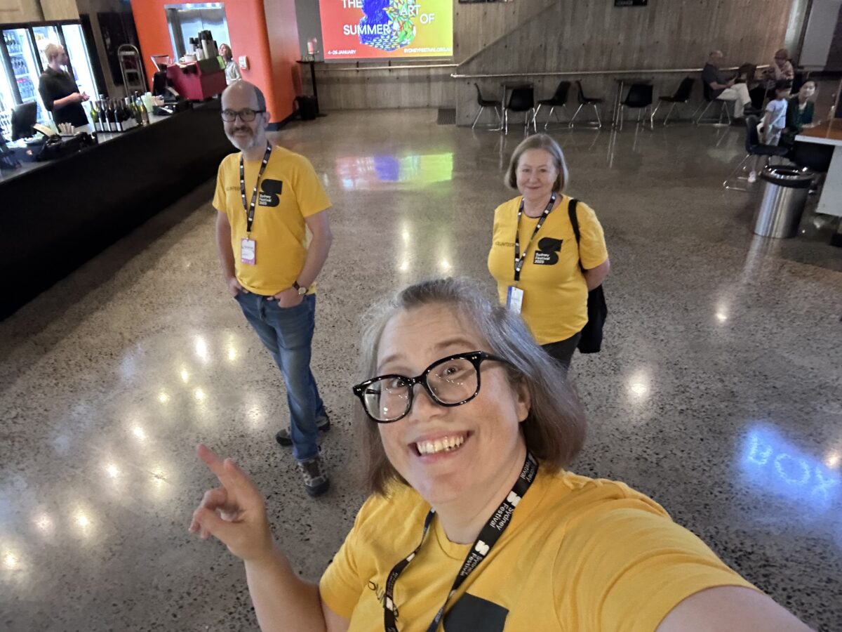 A selfie of three people in yellow t-shirts in the lobby of a theatre