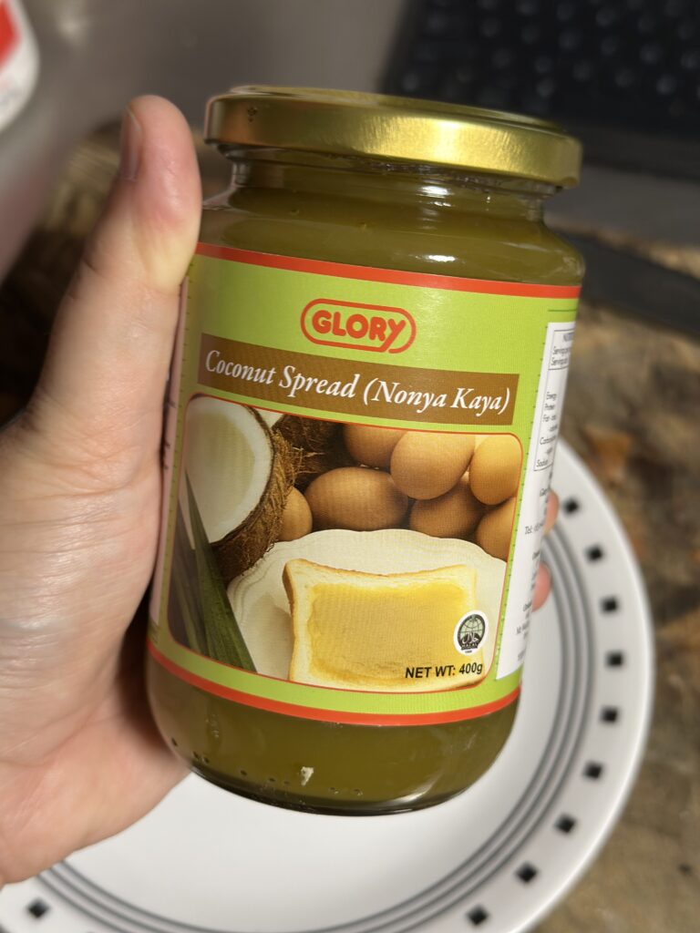 A hand holding a jar of light green paste with a label that says Coconut Spread (Nonya Kaya)