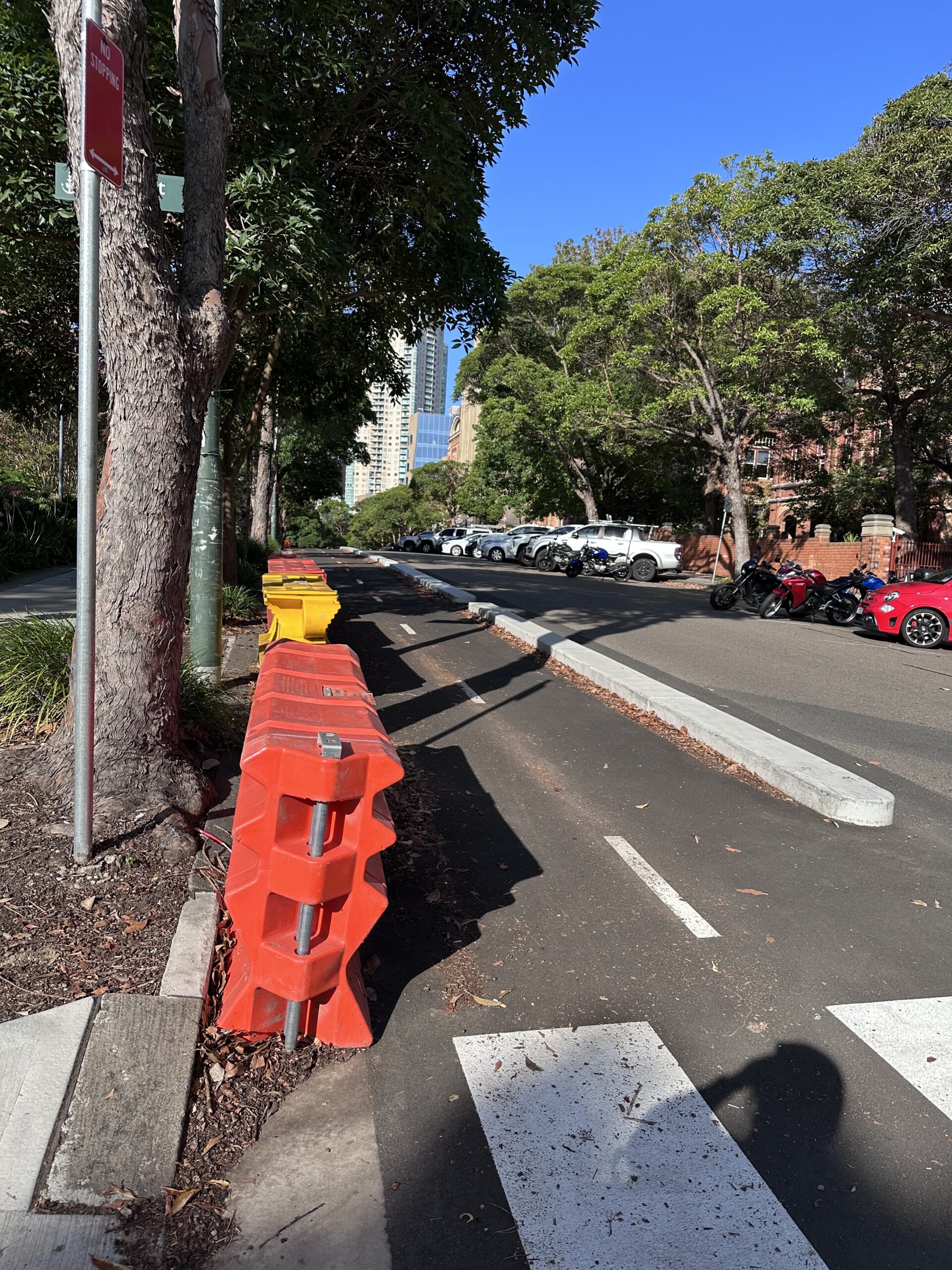 A separated two-way cycleway along a street. There are some large plastic barriers off to one side.