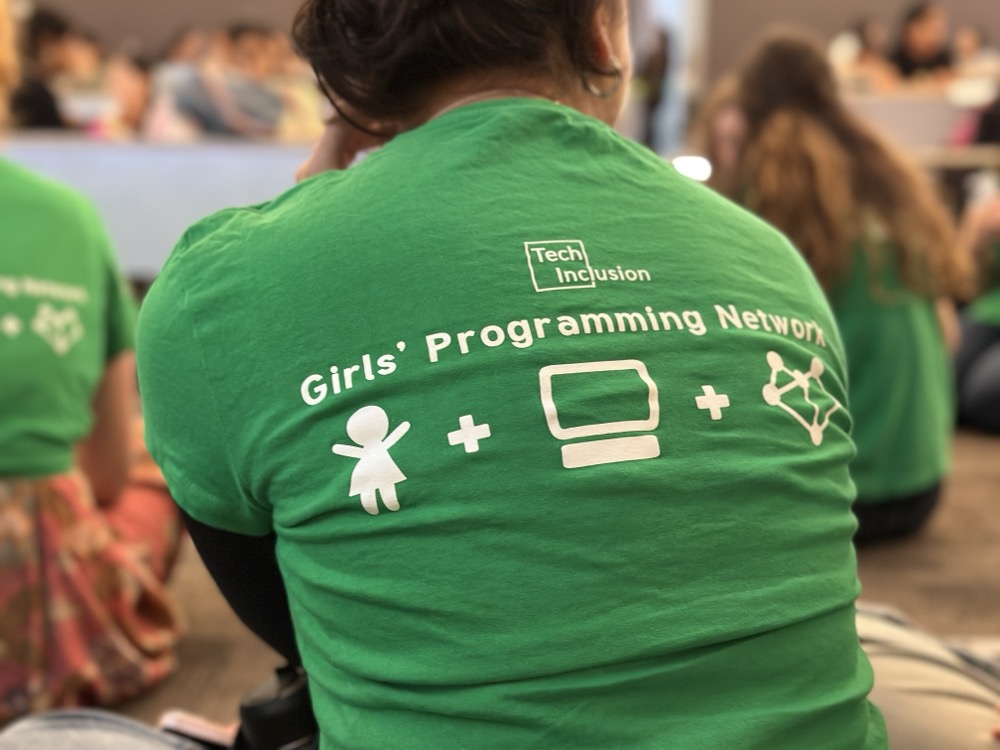 The back of a woman’s green t-shirt that says Girls’ Programming Network