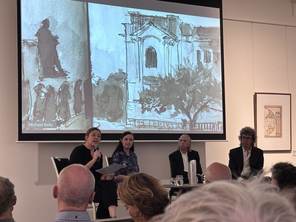 Four people in chairs on stage in front of an audience