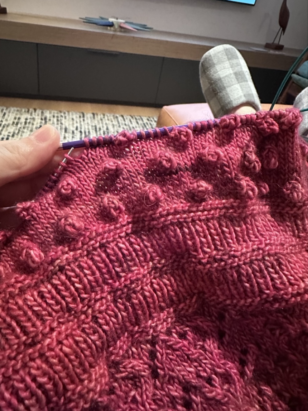 A piece of knitting in pink wool with rows of bobbles that look like… nipples. 